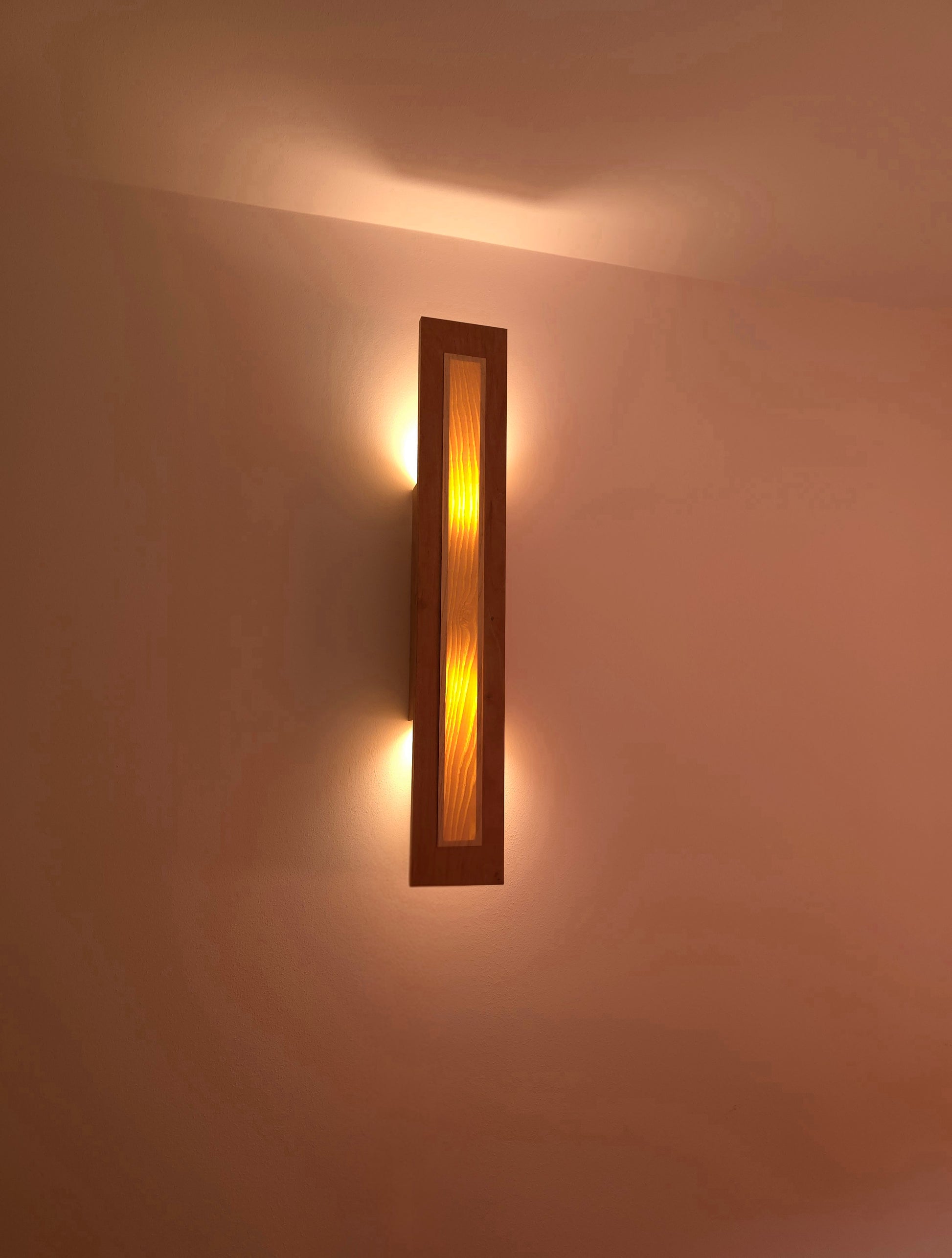 Applique Halo par Uphile, noyer et placage frêne, vue allumée avant.