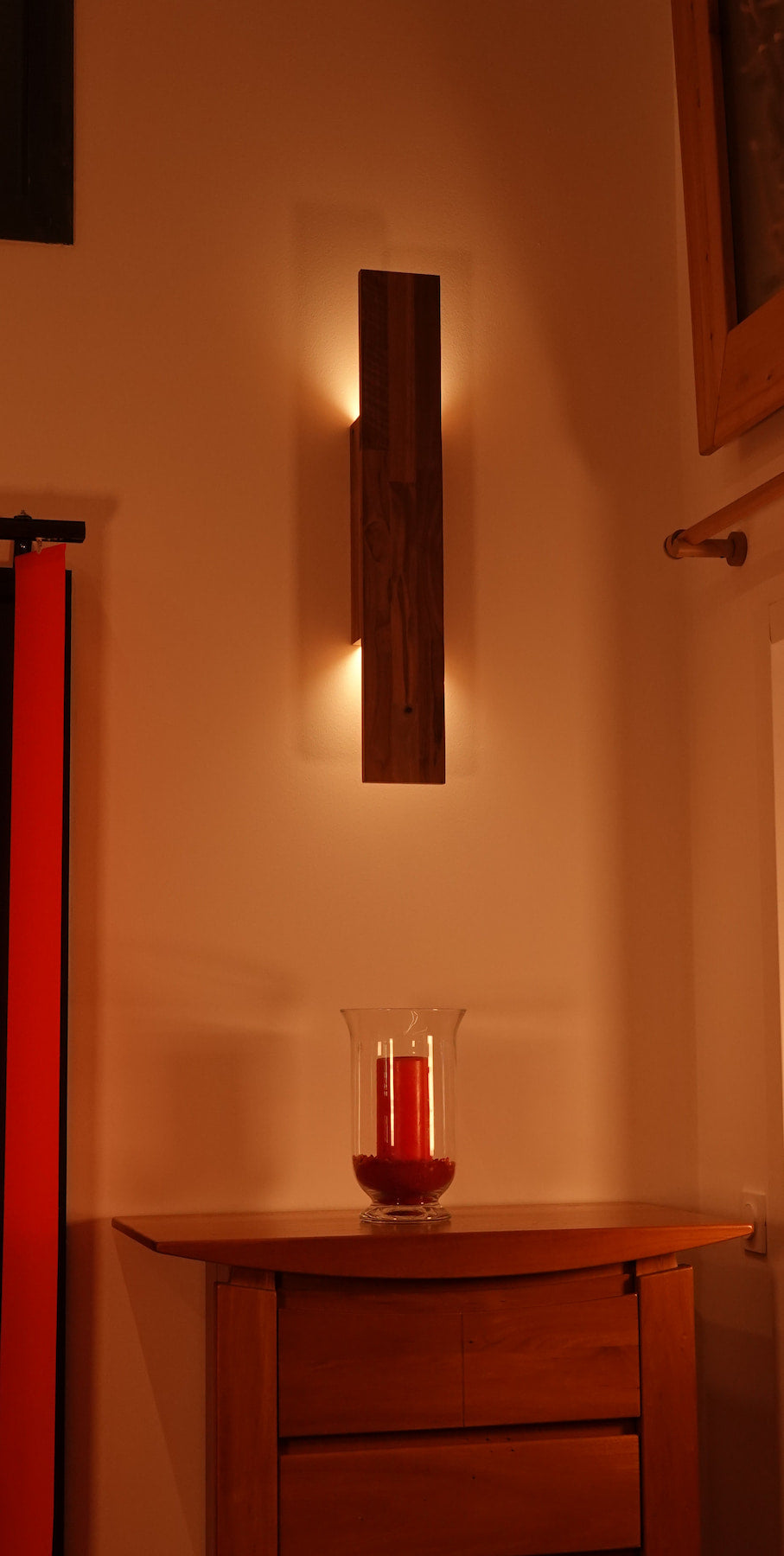 Applique Flambeau de chez Uphile, allumée, vue face avant gauche avec bougie posée sur une commode.